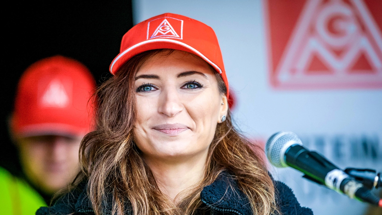 Eine Frau mit langem braunem Haar und IG Metall-Kappe blickt lächelnd in die Kamera.