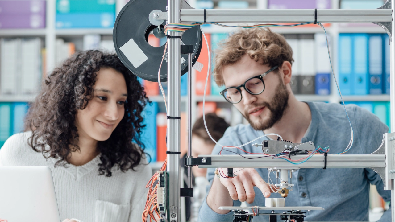 Zwei junge Ingenieure arbeiten an einem 3D-Drucker.