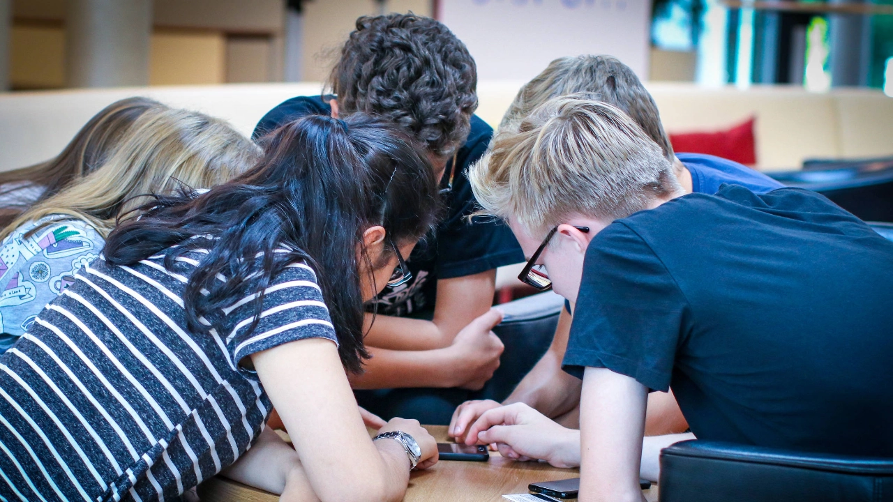 Eine Gruppe Jugendliche schaut gemeinsam in ein Handy.