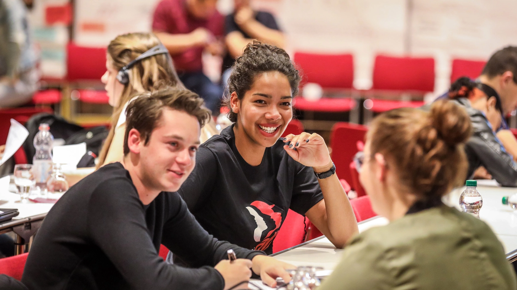 Eine Gruppe junger Menschen sitzt bei einer Konferenz zusammen und unterhält sich.