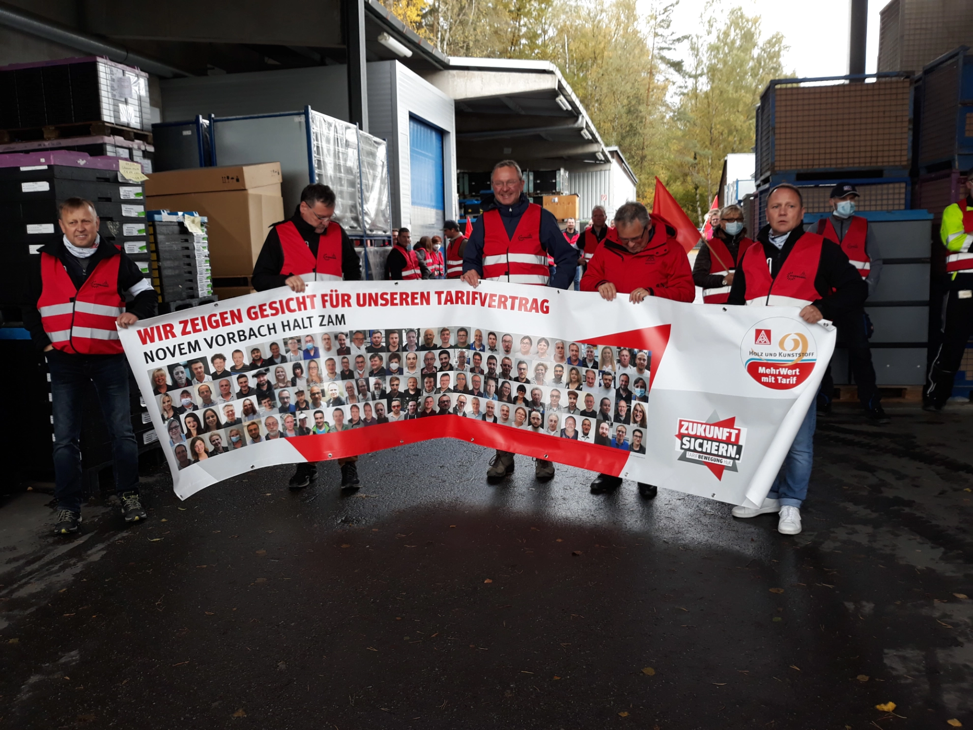Kollegen halten Banner mit Gesichtern beim Warnstreik