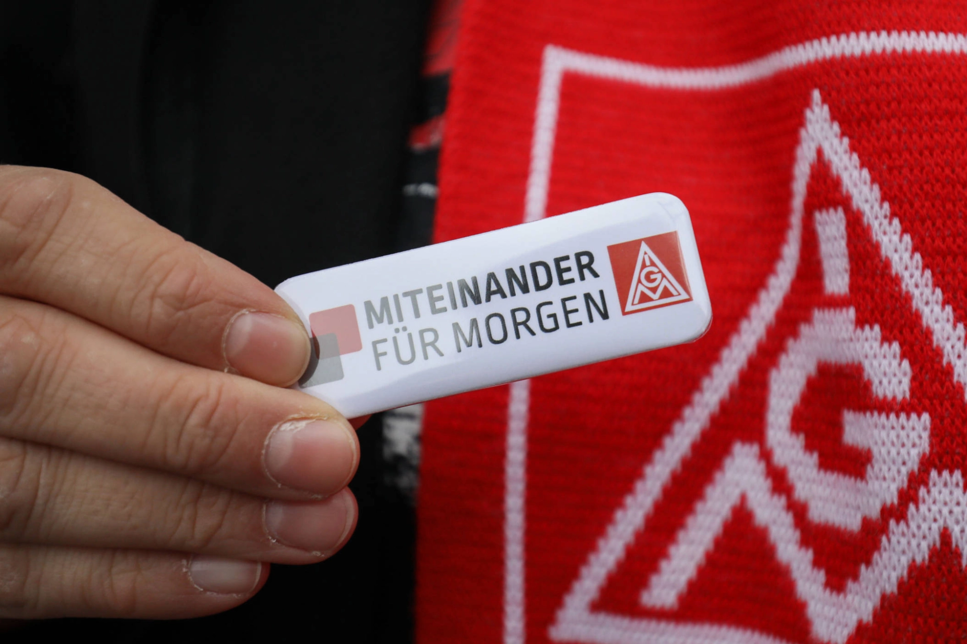 Jemand hält einen Anstecker mit der Aufschrift "miteinander für morgen".