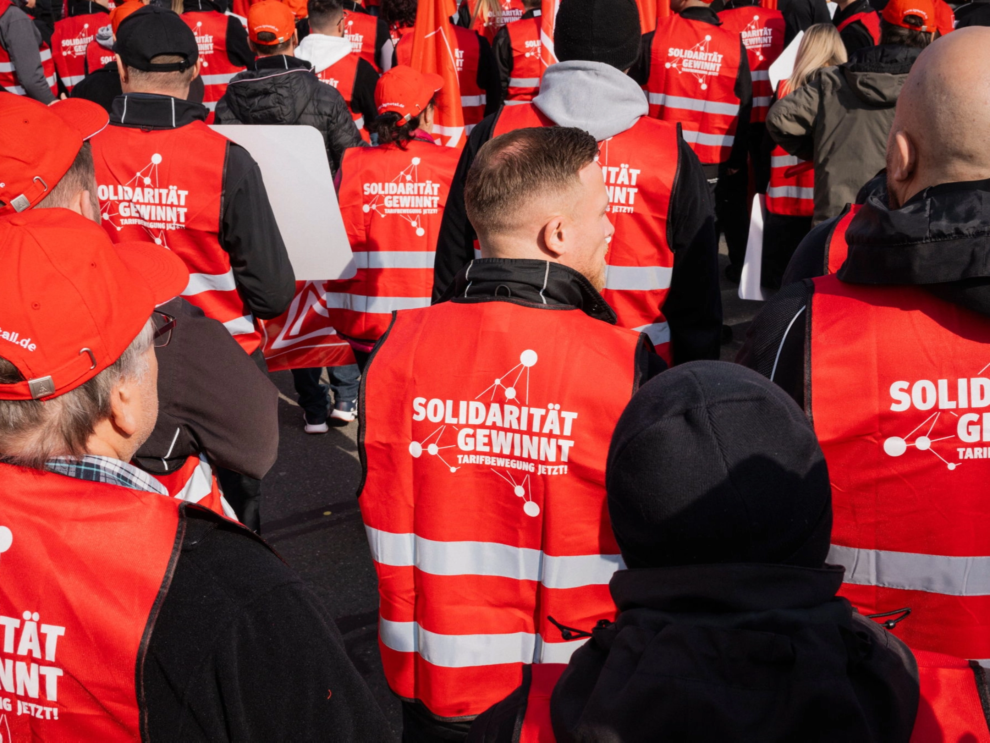Beschäftigte tragen rote Westen mit dem Aufdruck „Solidarität gewinnt. Tarifbewegung jetzt“ auf dem Rücken