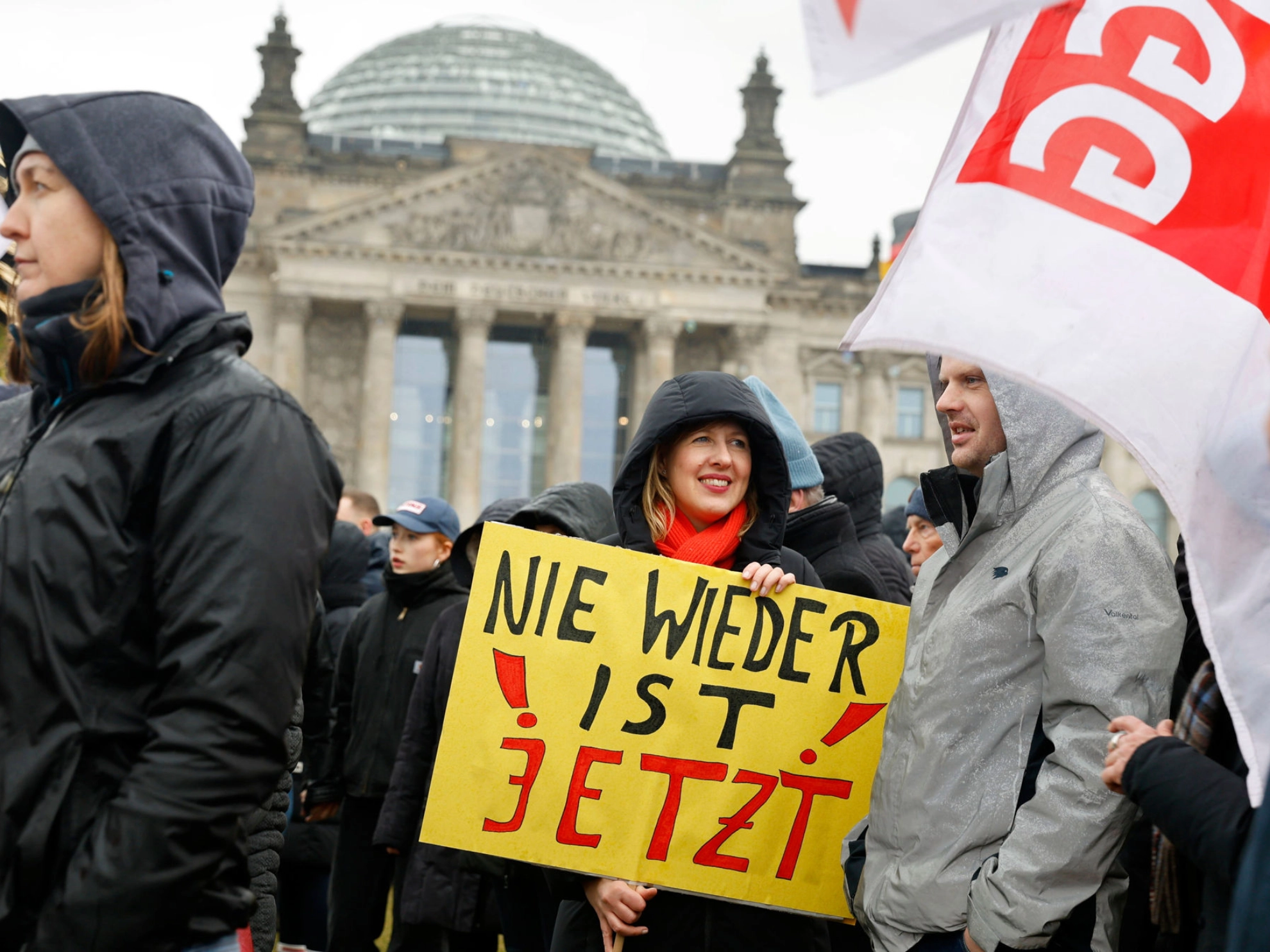 In der Menschenmenge bei einer Demo trägt eine Frau ein Schild mit der Aufschrift „Nie wieder ist jetzt“.