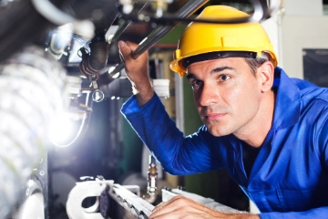 Arbeiter an einer Maschine in einer Produktionshalle